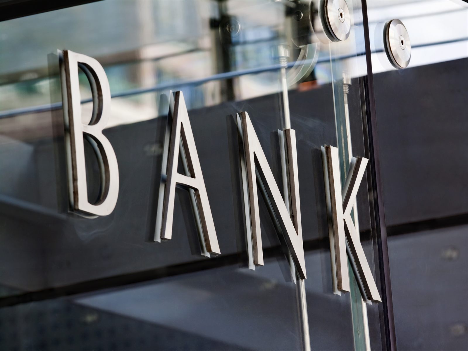 Metal lettering spelling Bank fixed to a reflective glass wall
