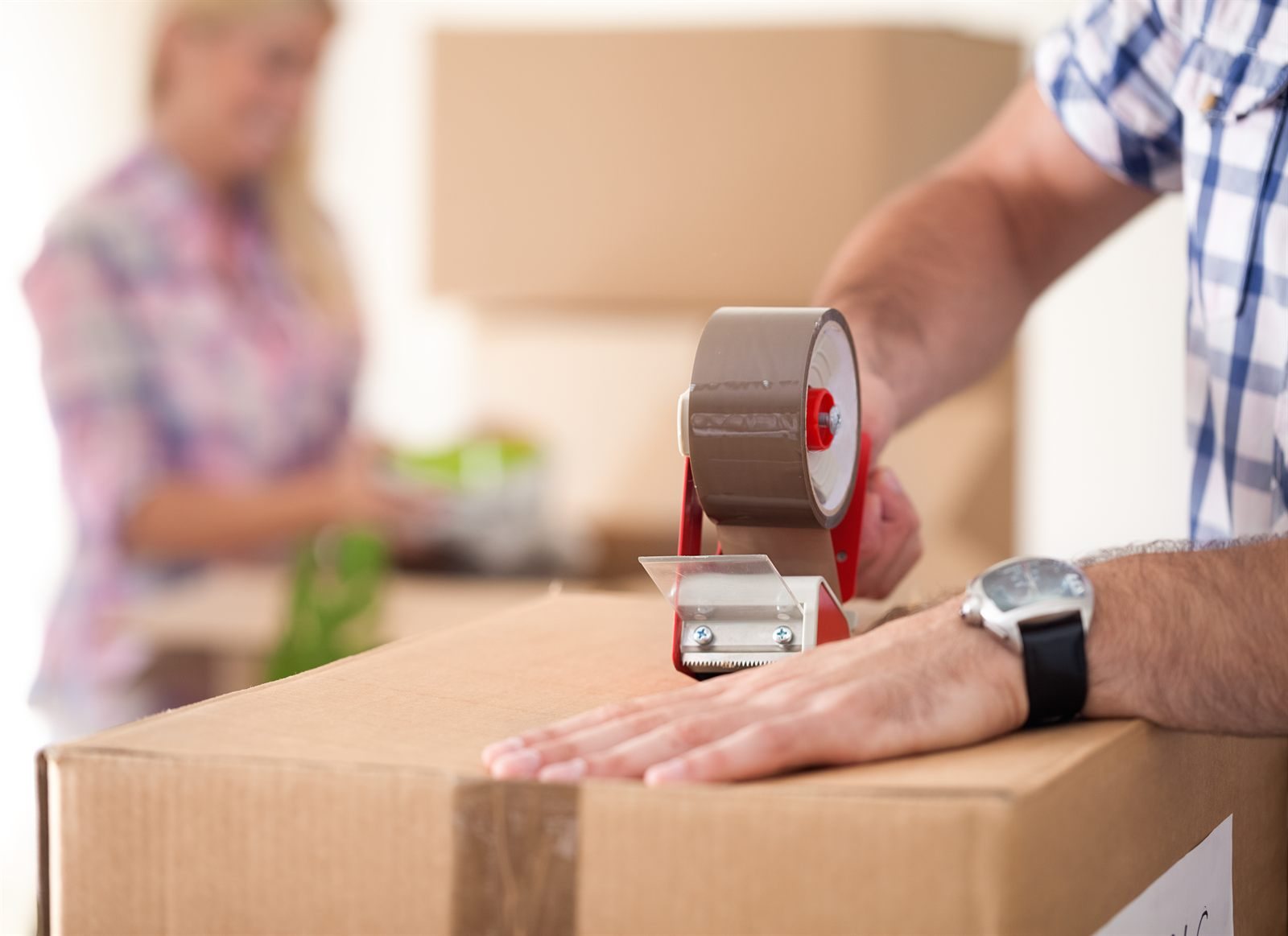 Hands taping a cardboard moving box closed