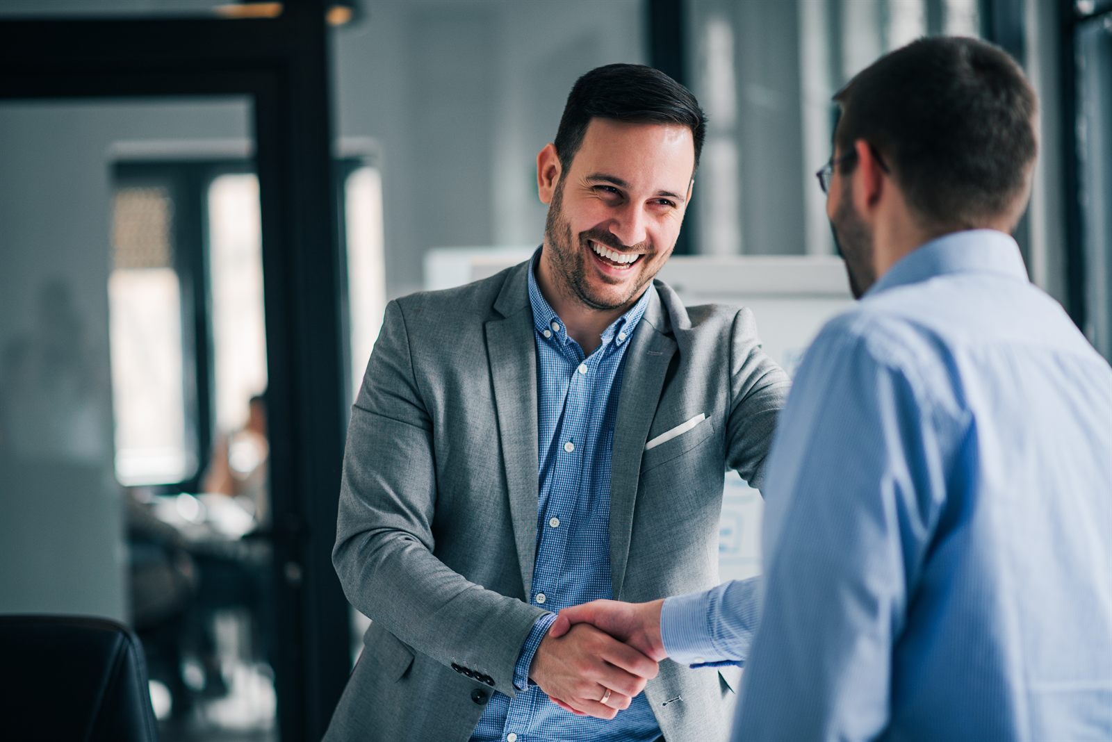 Two people shaking hands across a desk after reaching an agreement
