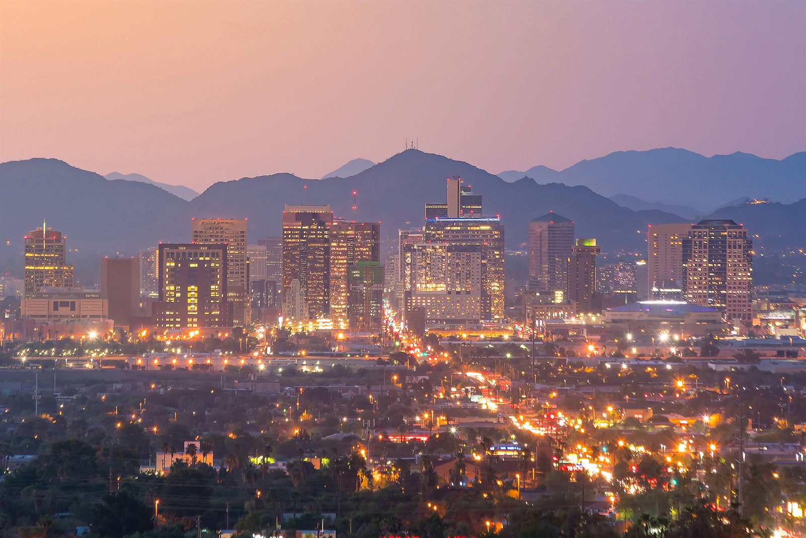 A downtown city skyline lit at dusk