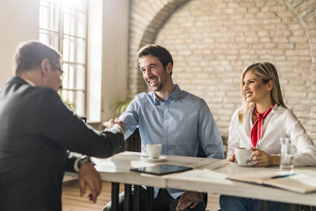 A couple reviewing paperwork with their agent at an office desk