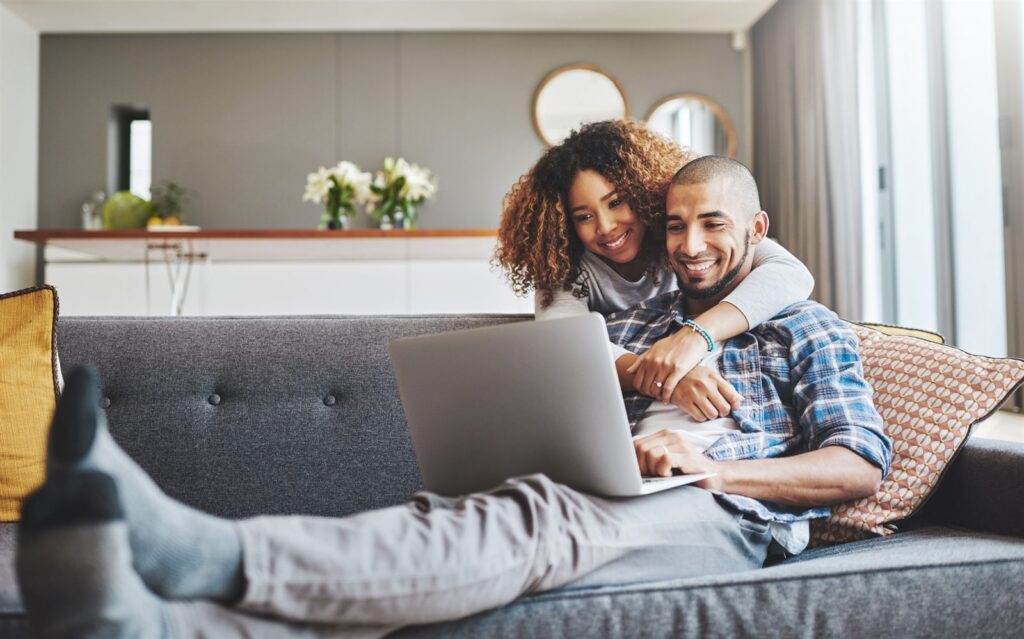 A couple sitting on a sofa looking at a laptop together