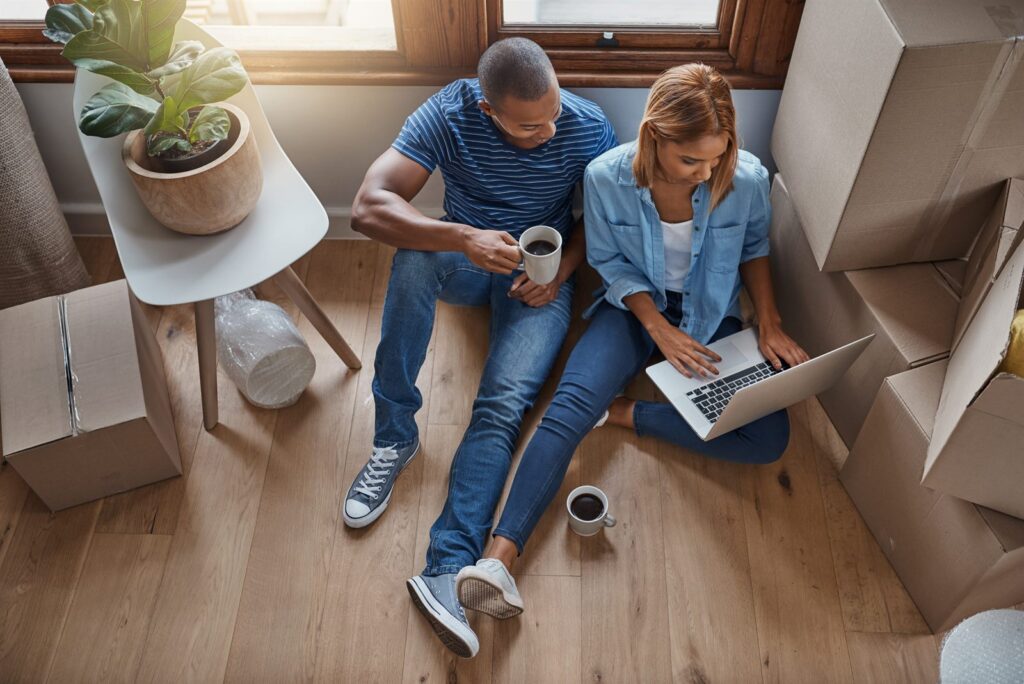 A couple sitting with a laptop among moving boxes