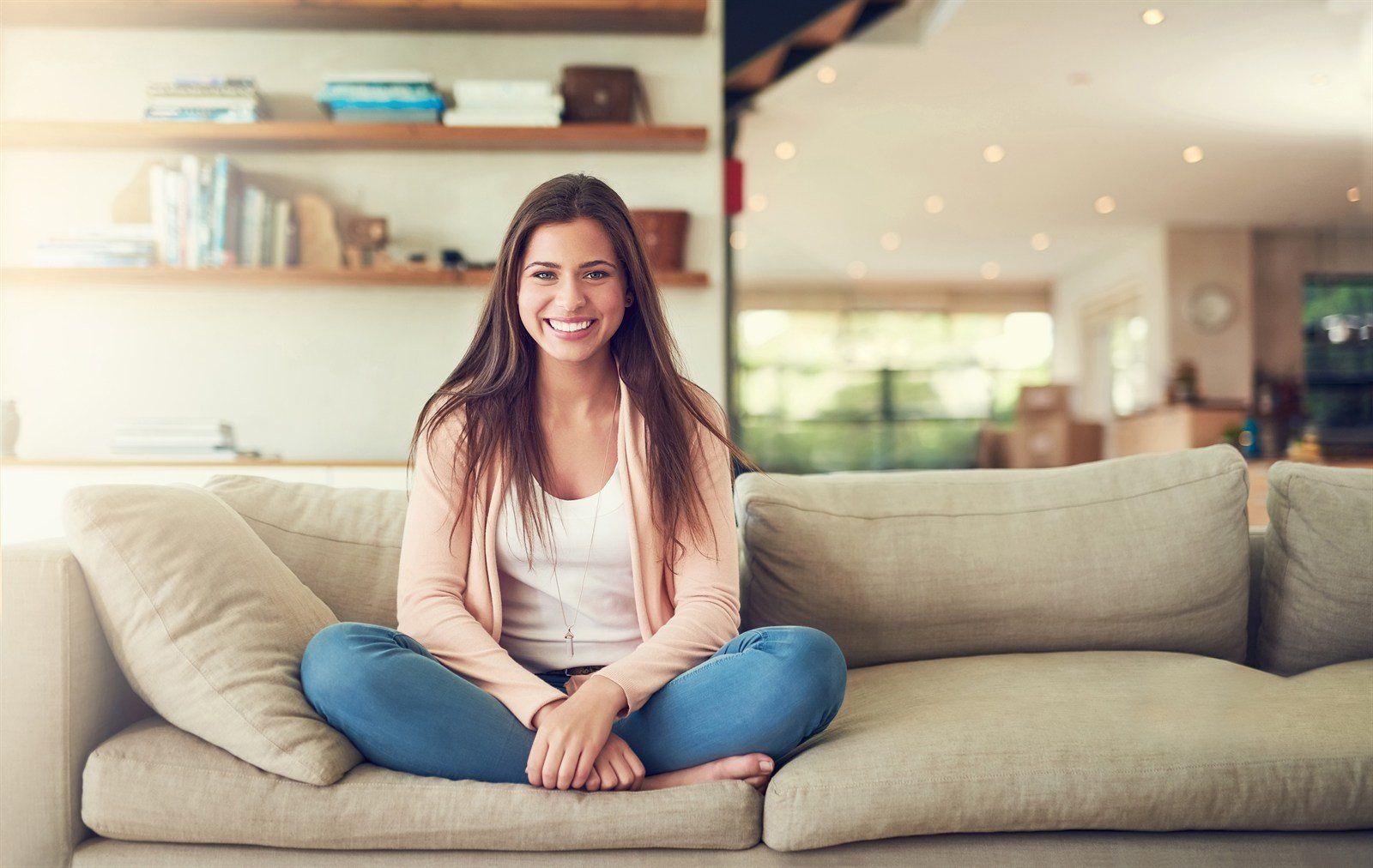 A woman sitting on a sofa in a bright, finished living room
