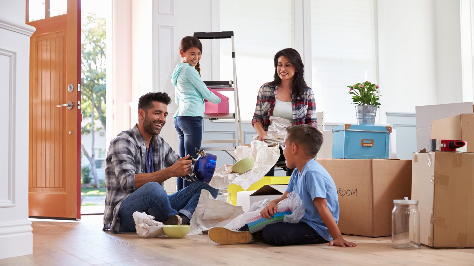 First-time homebuyers unpacking moving boxes in the entryway of their new house