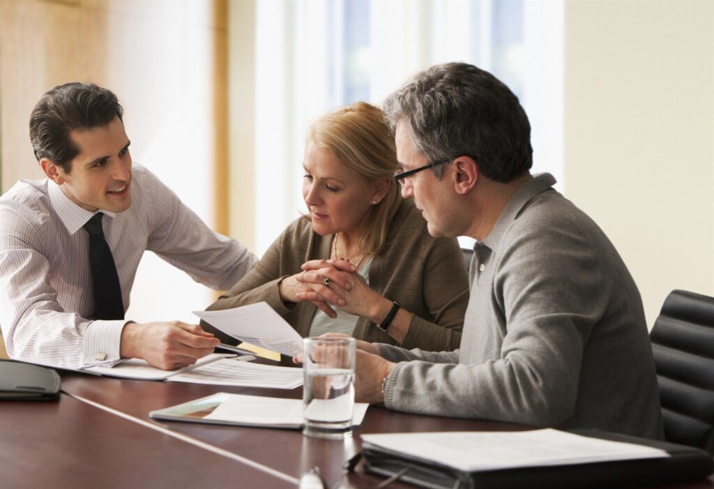 Three people reviewing documents together at a boardroom table