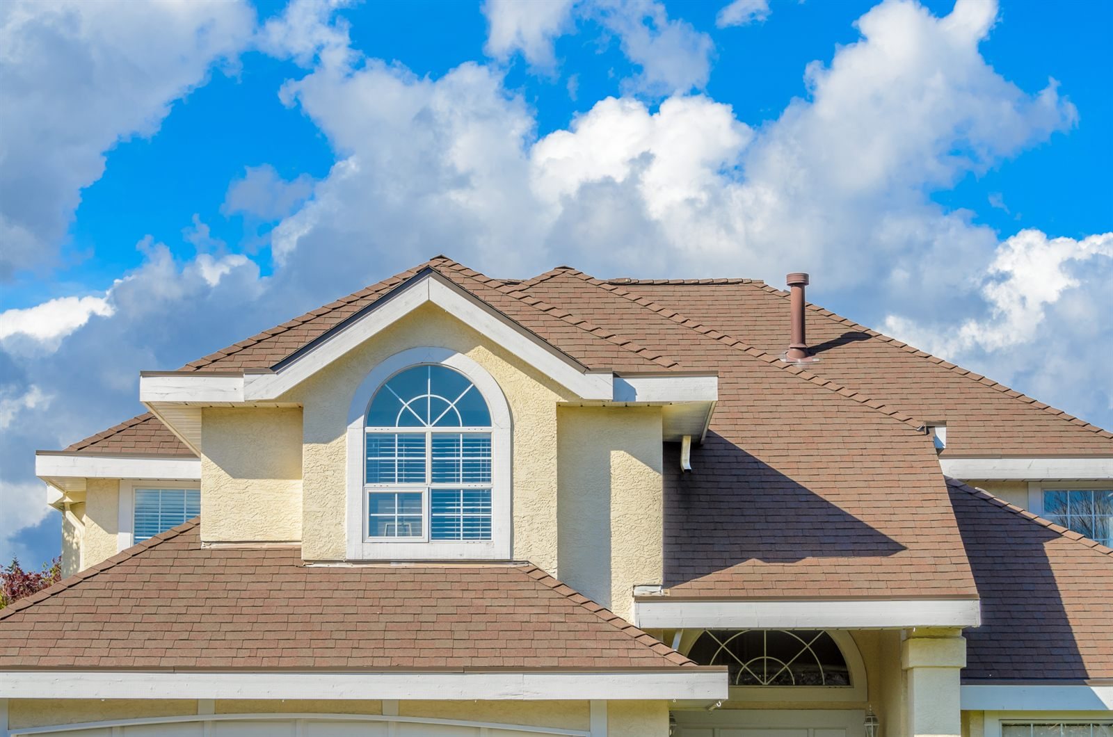 Residential roof and dormer against a blue sky
