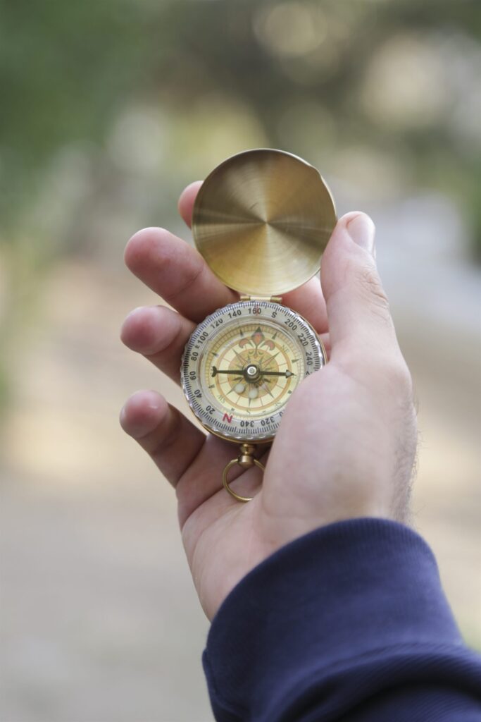 A hand holding a brass compass