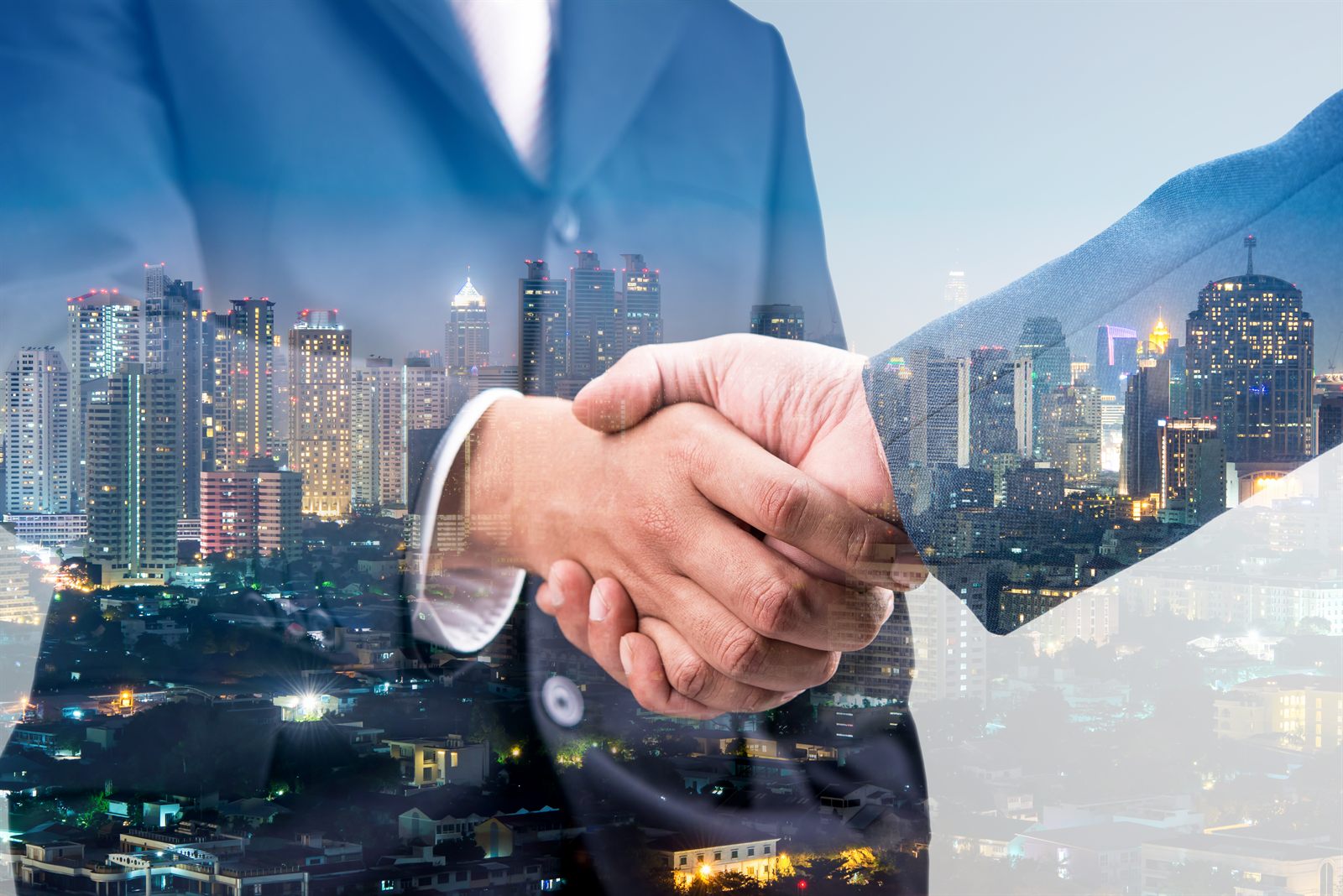 A handshake overlaid on a city skyline at night