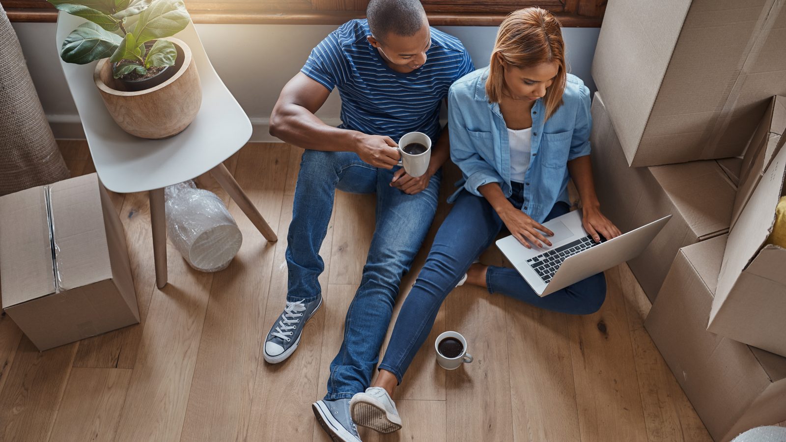 A couple sitting among moving boxes reviewing mortgage options on a laptop