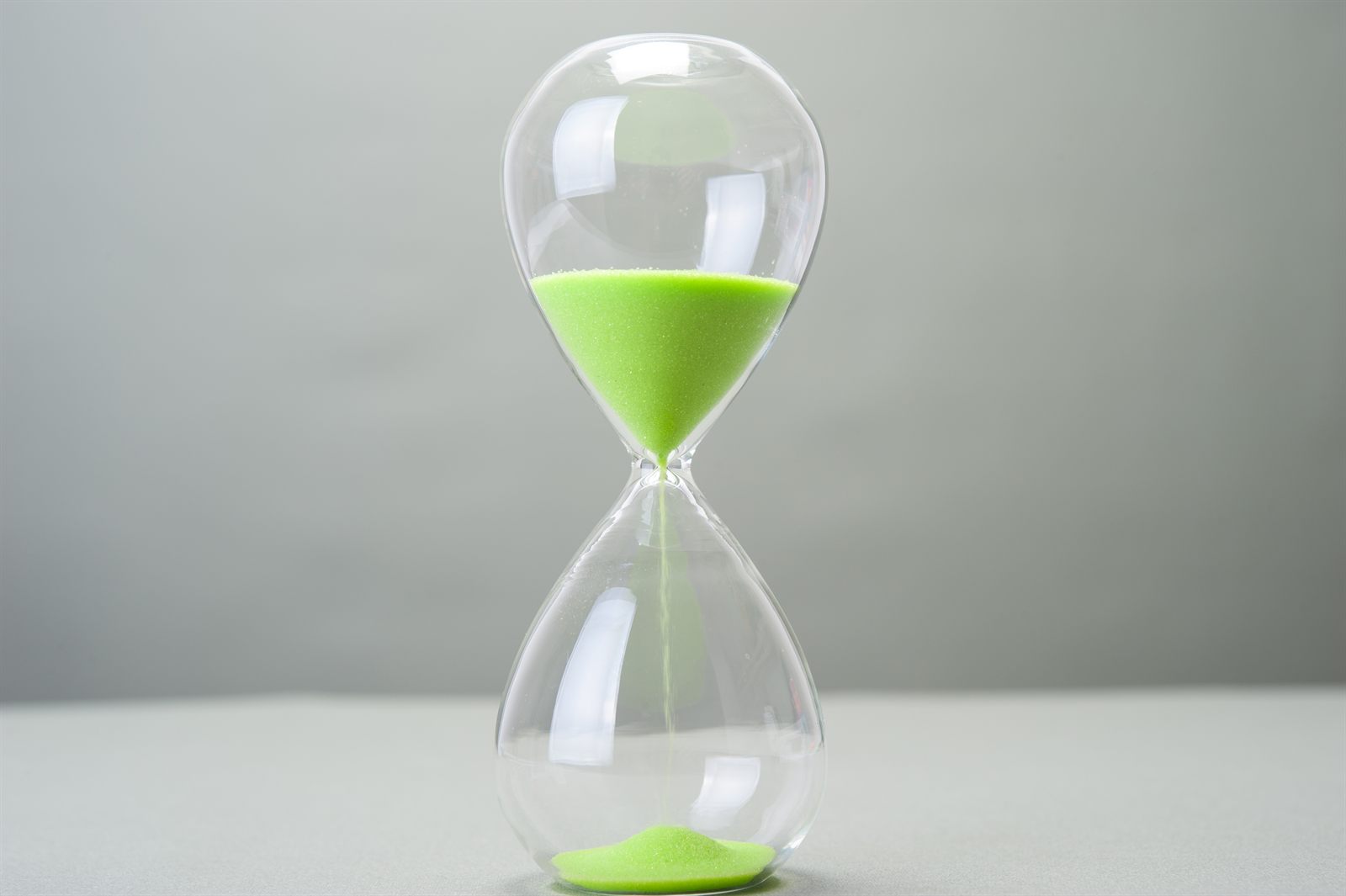 A green hourglass with the sand running through