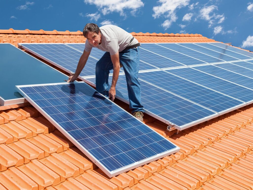 A worker installing solar panels on a roof