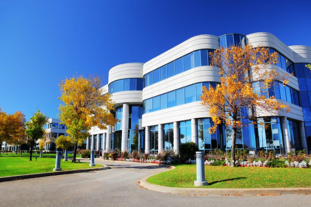 A glass-fronted commercial office building in a landscaped office park