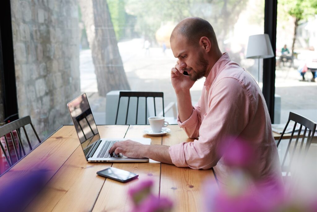 A business owner working on a laptop at a cafe table