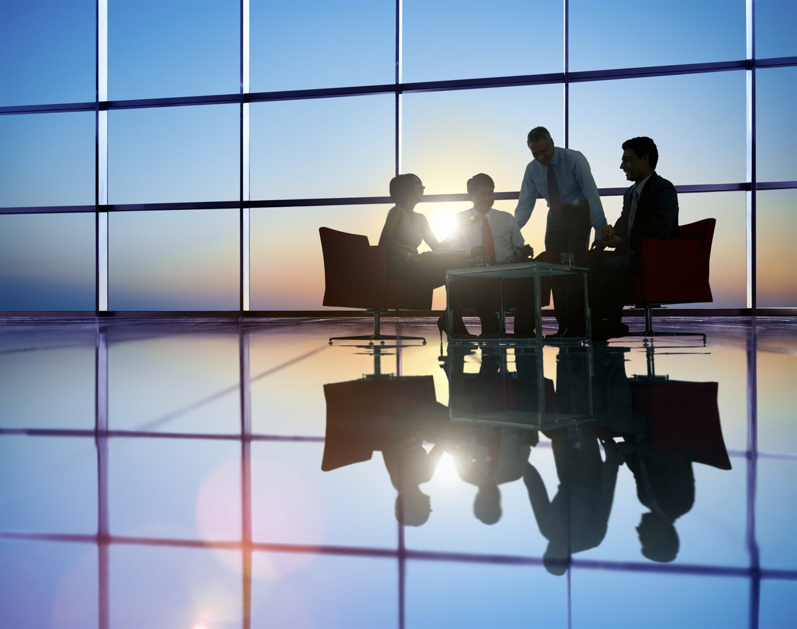 Silhouetted figures meeting around a boardroom table