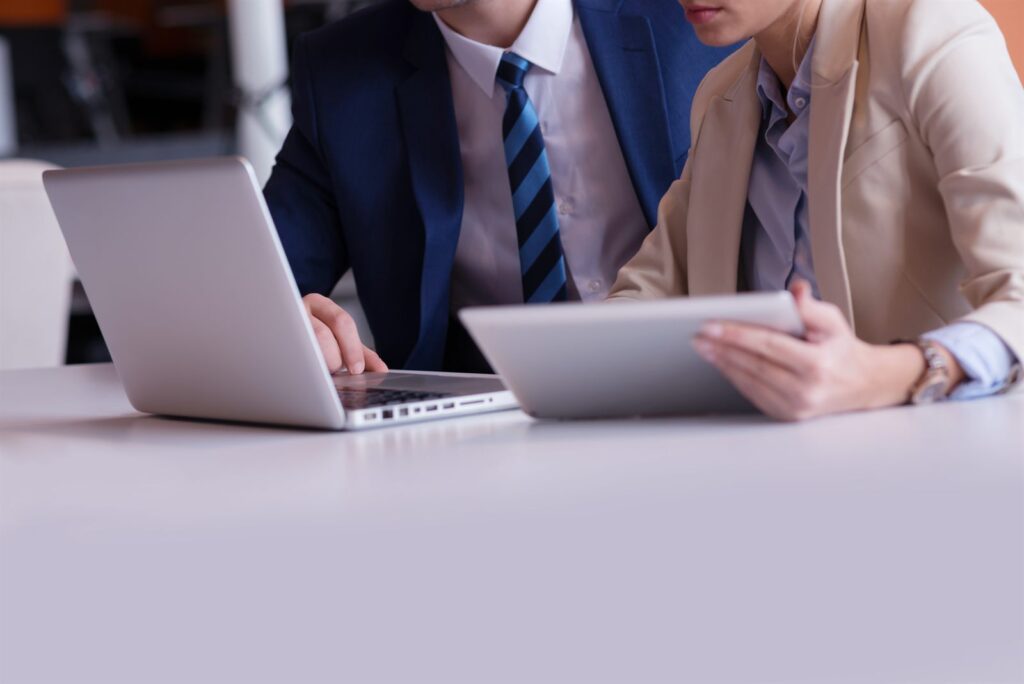 Two people working on laptops across a table