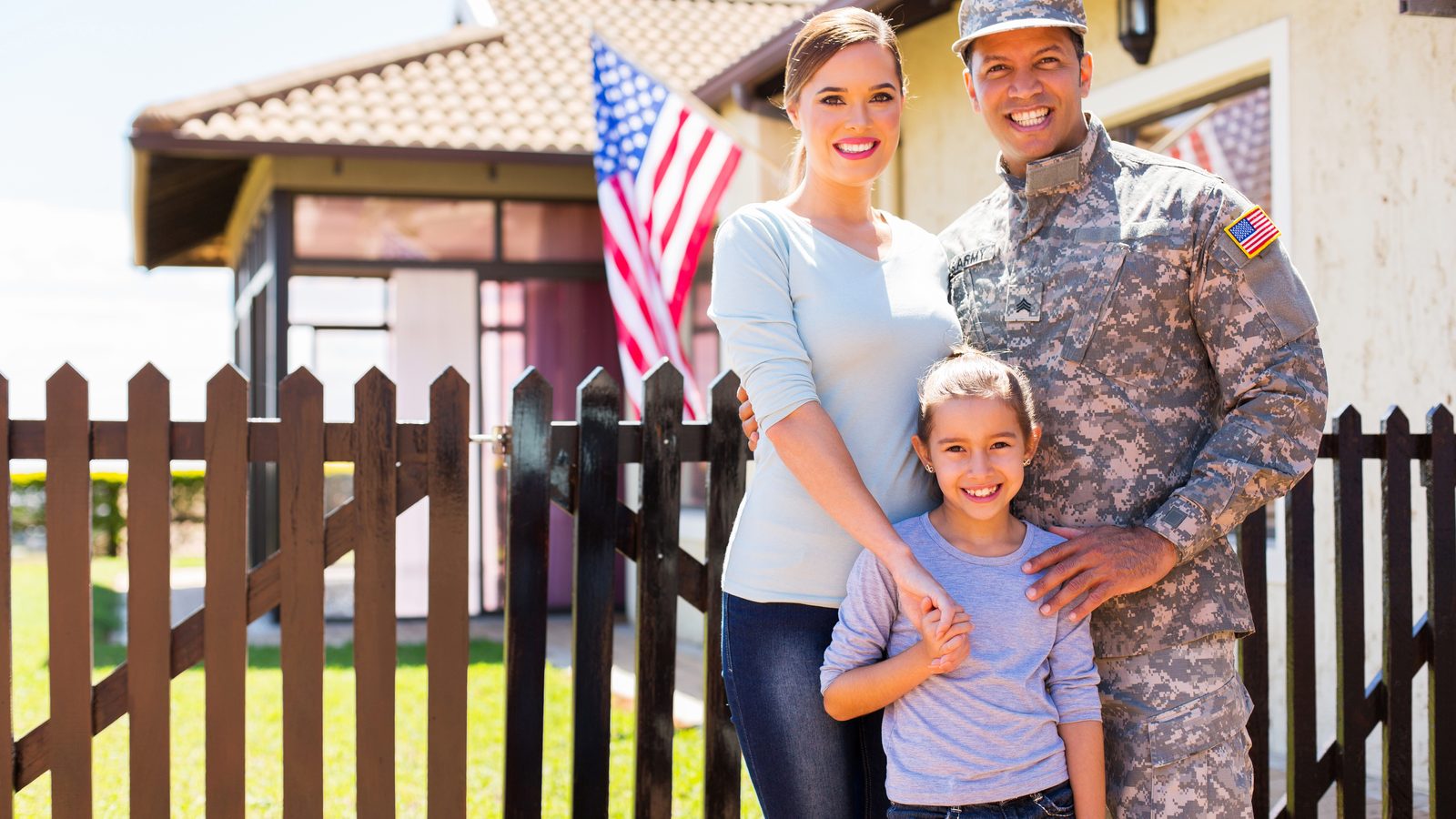 A military family standing with an American flag in front of their home