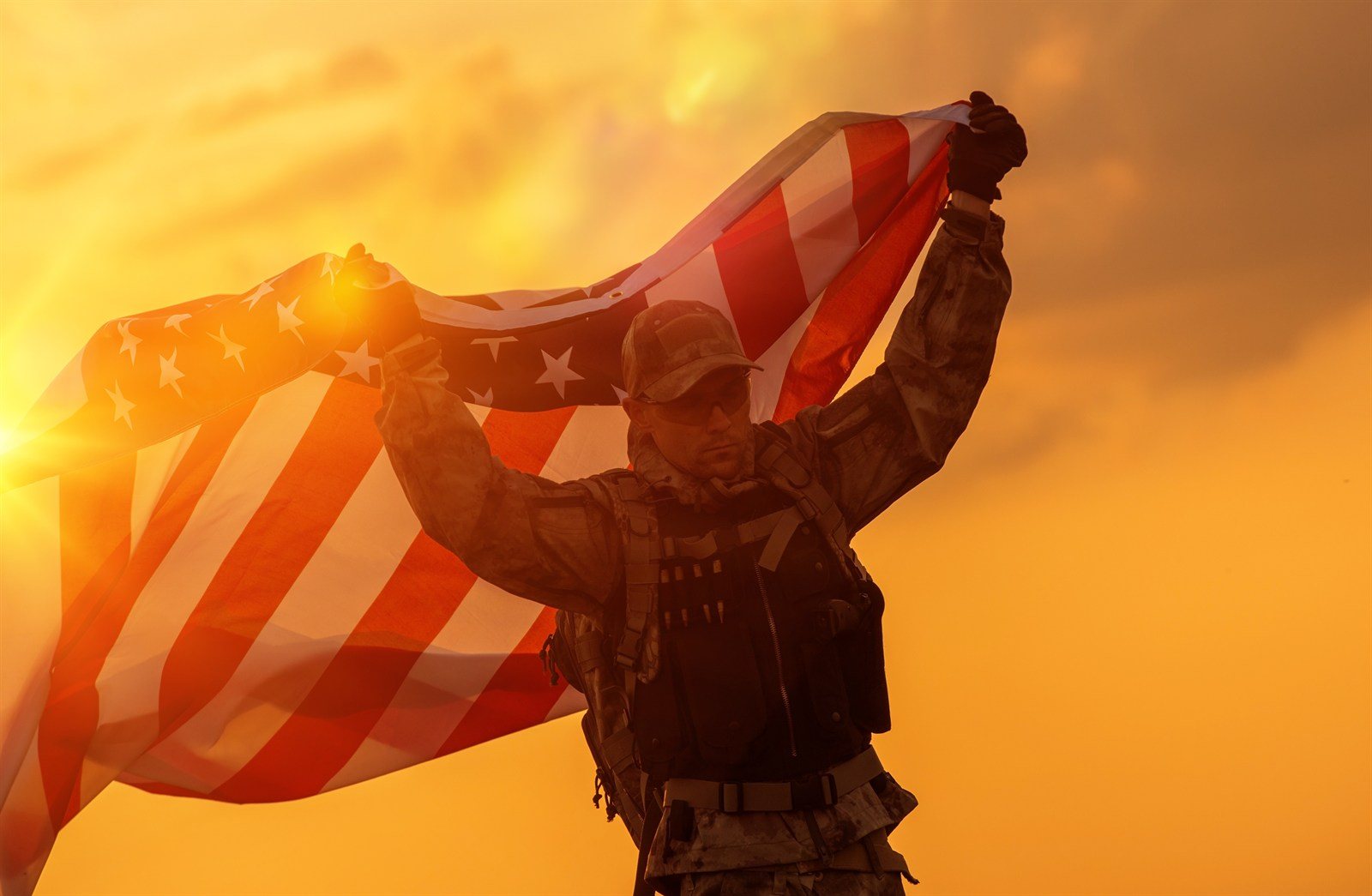 A service member holding an American flag at sunset