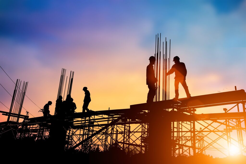 Construction workers silhouetted on steel framing at sunset